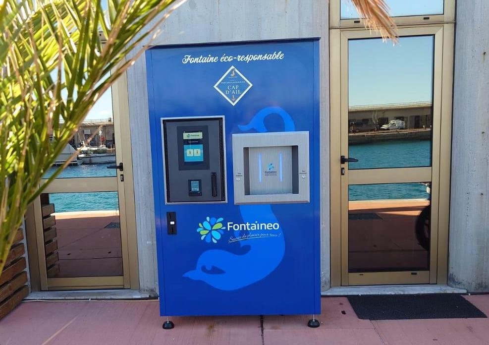 Modèle de fontaine à eau Money'O de Fontaineo, installée au Cap d'Ail, en France, près du bord de mer. La fontaine à eau potable dispose d'un appareil de paiement, et de deux buses pour recharger des gourdes d'eau.