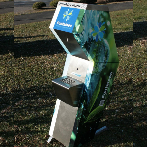 Un distributeur d'eau moderne et angulaire, baptisé « Fontaineo » et « PRIMO light », est installé sur une pelouse. Son design dynamique, avec des images d'eau et de feuilles, est équipé d'un bac et d'un distributeur.