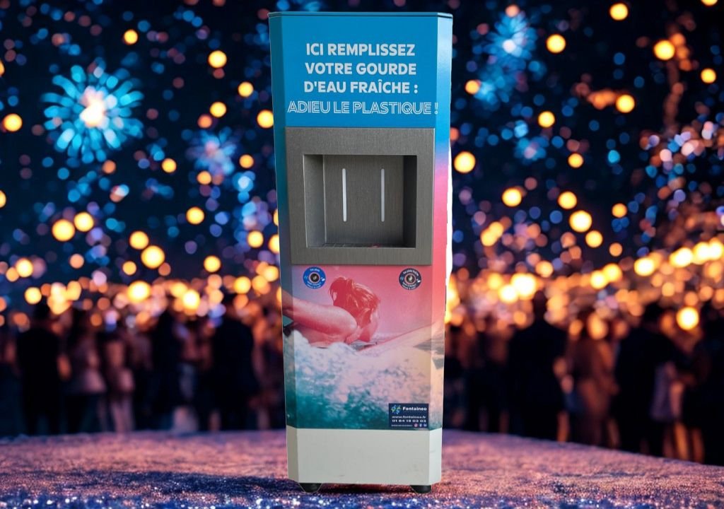 Una estación de llenado de agua con texto en francés se alza de noche frente a una multitud borrosa, con muchas luces brillantes y un ambiente festivo de fondo.