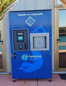 Modèle de fontaine à eau Money'O de Fontaineo, installée au Cap d'Ail, en France, près du bord de mer. La fontaine à eau potable dispose d'un appareil de paiement, et de deux buses pour recharger des gourdes d'eau.