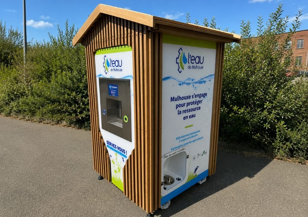 Un petit kiosque en bois portant la mention « L'eau de Mulhouse » permet de se servir de l'eau. Installé sur le trottoir, à proximité d'espaces verts et d'un immeuble, il est équipé d'un robinet, d'un distributeur de gobelets, d'instructions et d'un texte multilingue sur la préservation de l'eau.